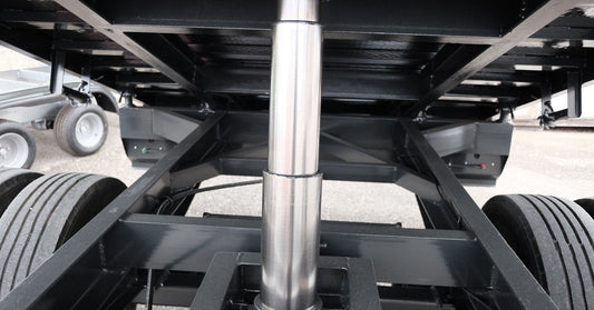 A focus shot of a pristinely clean silver and black hydraulic lifting system, holding up the trailer of a truck.