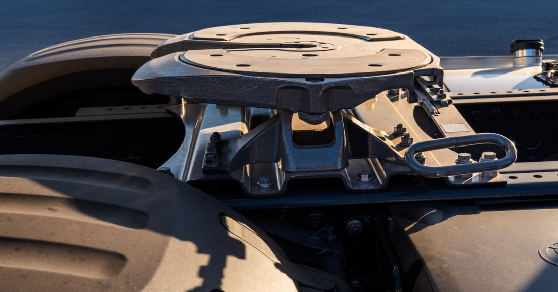 A close view of a truck chassis showing a mounted fifth wheel plate with visible locking jaws and frame rails beneath.