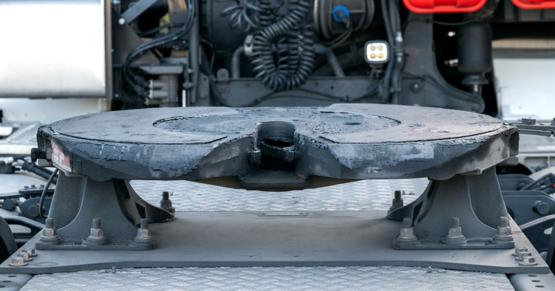 A close view of a fifth wheel hitch on the back of a semi-truck, with the air and electrical connections visible.